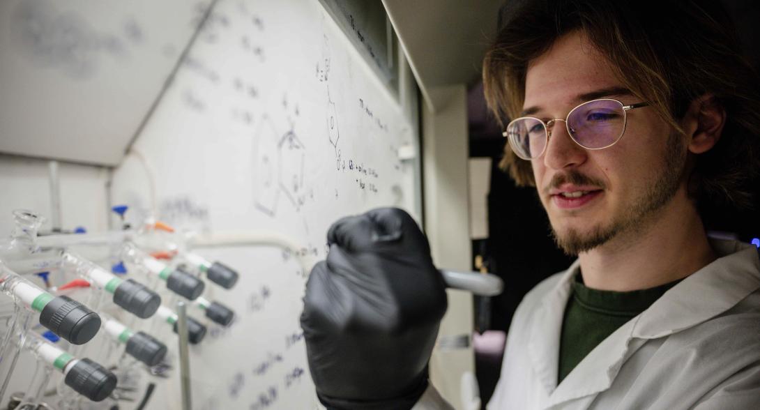 Matthew Reeves writes on a clear board in the chem lab.